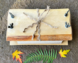 A one of a kind live edge birch wood flower press is displayed with leaves and fern in the foreground. Handmade flower press from Pressed Wishes. 