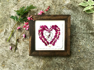 Pressed Bleeding Heart flowers arranged in the shape of a heart in a solid walnut stained frame. Handmade in Canada by Pressed Wishes.