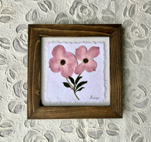 Two pink dogwood flowers are pressed and set on white handmade papers. They are framed with a solid wood handcrafted frame, finished with a walnut stain. Pictures come with 2ml glass. Artwork by Pressed Wishes, Canadian botanical artists. 