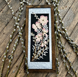 Pressed flowers are arranged in a floral bouquet containing pink dogwood, pussy willow and musk mallow. The floral bouquet is framed and available to hang on the wall as wall art. Handmade by Pressed Wishes.