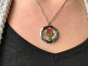 Real pressed red rosebud locket necklace on model by Pressed Wishes. The locket is made of silver stainless steel and glass. Model wears an 18 inch chain. Proudly handmade in Canada